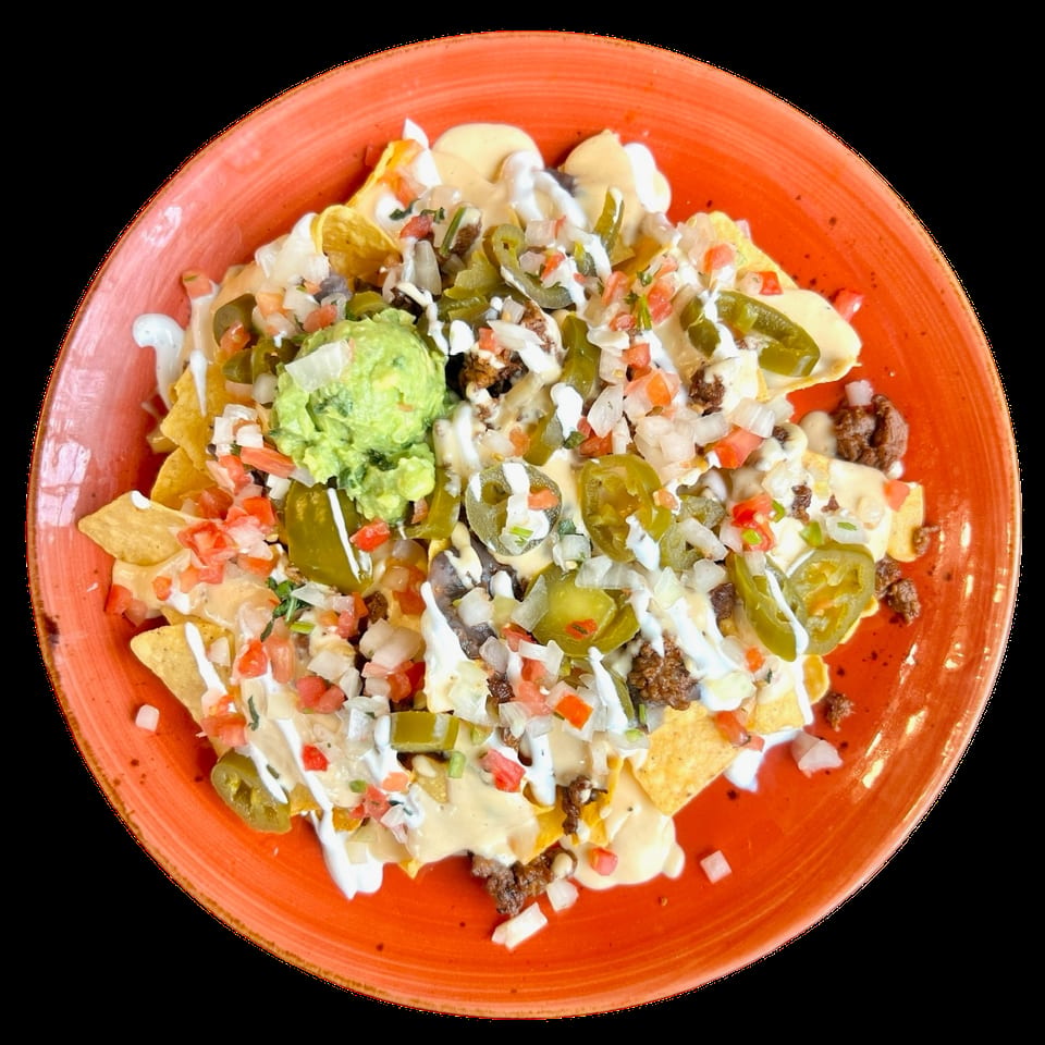 Nachos on an orange plate, topped with cheese, ground beef, guacamole, pico de gallo, and jalapeños.
